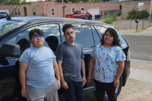 Veronica with her two children in front of the family car